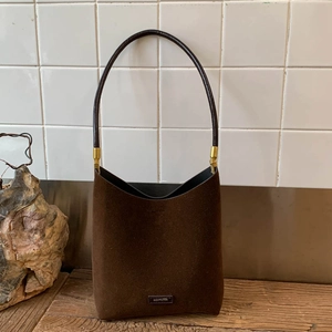 Detailed view of coffee suede shoulder bag featuring a gold NO FILTER metal plaque logo