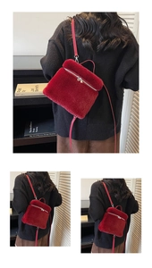 Detail eines roten Plüsch-Rucksacks mit silbernem Reißverschluss und schmalem Trageriemen
