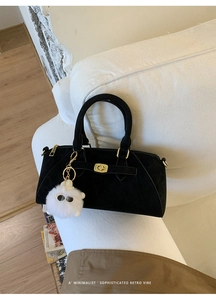 Dettaglio borsa nera con chiusura girevole dorata e ciondolo agnello di peluche bianco