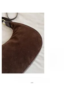 Macro detail of dark brown suede crescent bag with metallic gold ring and smooth leather trim