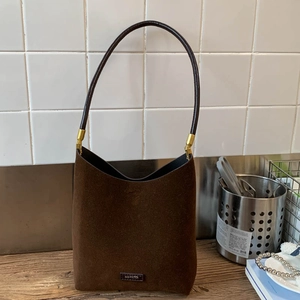 Detail of suede tote bag in dark brown with gold metal hook and leather strap