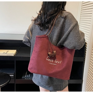 Burgundy tote bag detail showing soft velvet texture and shoulder strap fit