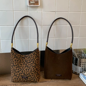 Detail of leopard print and dark brown suede bucket bags with metallic gold hardware