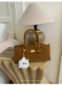 Dettaglio borsa retrò in pelle marrone con chiusura dorata e ciondolo di peluche