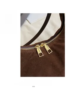 Close-up of smooth gold dual zippers on a dark brown suede leather commuter handbag