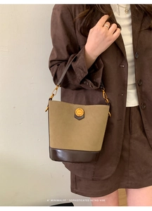 Detail of khaki suede bucket bag with brown leather base and gold fashion hardware