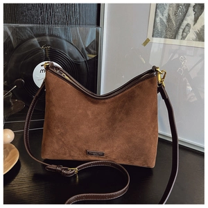 Dettaglio della borsa tote in pelle scamosciata marrone con placca vintage su legno