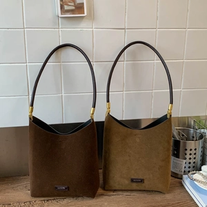 Detail view of suede bucket tote bags in coffee and khaki with No Filter leather patch