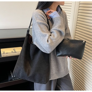 Detail showing the large black suede bucket tote bag with its matching zipper pouch