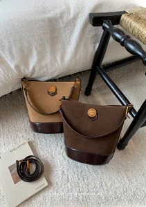 Detail of vintage suede bucket bags showing premium leather stitching and gold metal buckle
