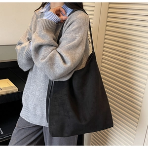 Side view of a vintage black suede bucket bag worn as a spacious commute tote