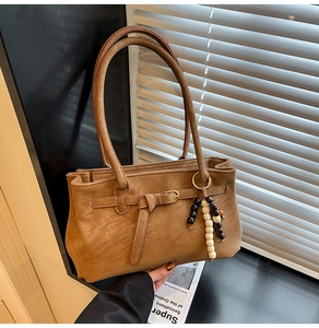 Detail view of brown faux leather bucket bag featuring beaded tassel and buckle closure