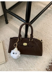 Dettaglio borsa a mano in pelle scamosciata marrone con chiusura dorata e charm di peluche