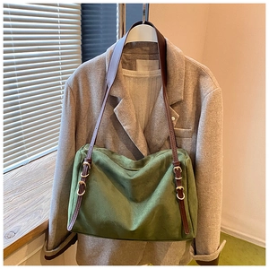 Detail of green suede tote bag with brown leather shoulder straps and gold hardware buckles