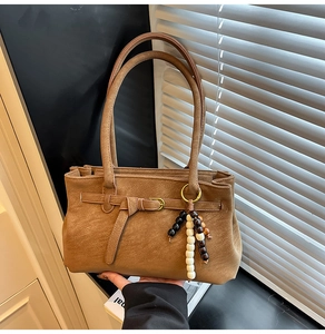 Detail of caramel vintage matte leather shoulder bag with decorative beaded tassel charm