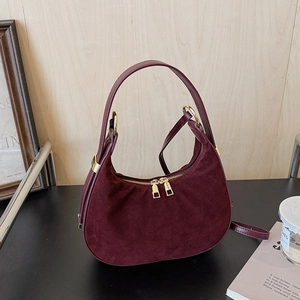Macro shot of burgundy suede texture on hobo bag with gold zippers and hardware