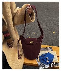 Dettaglio di una borsa a secchiello vintage bordeaux in stile Maillard con finiture oro