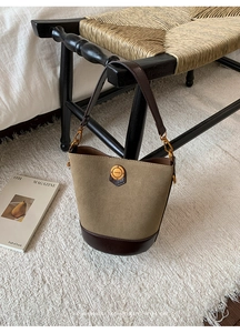Detailed macro view of retro suede bucket bag with gold fashion hardware on a wooden chair