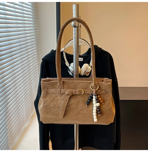 Detail view of vintage brown matte bucket bag with beaded charm and decorative buckle