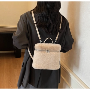 Detail eines weichen beigen Plüschrucksacks mit silbernen Reißverschlüssen und Lederriemen