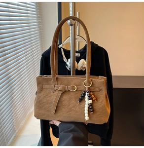 Detail view of vintage brown matte bucket bag with golden buckle and wooden bead charm