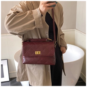 Borsa a tracolla trapuntata bordeaux indossata su un modello con chiusura dorata a scatto