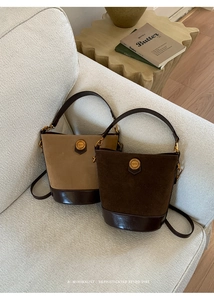 Detailed close-up of retro suede bucket bags in brown with polished leather trim