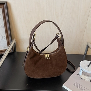 Detail view of the brown suede hobo bag showing gold zippers and leather stitching