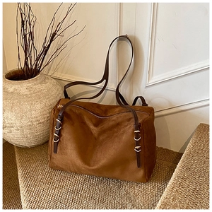 Detail of brown suede tote bag featuring leather straps and golden metal buckle