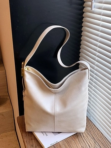 Grand sac seau blanc crème avec texture cuir grainé et boucle en métal sous lumière douce
