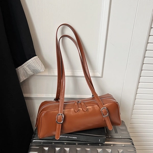 Close-up of brown faux leather shoulder bag with silver buckles on a silver suitcase