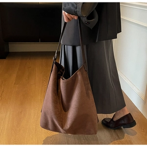 Detail of soft brown suede bucket bag texture shown during commute use as shoulder tote