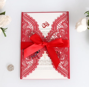 Detail of red laser-cut wedding invitation with silk ribbon and white printed inner card