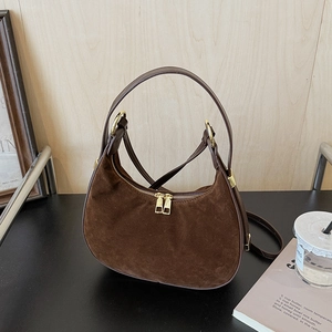 Detail of a dark brown suede hobo bag with gold zippers and adjustable shoulder strap
