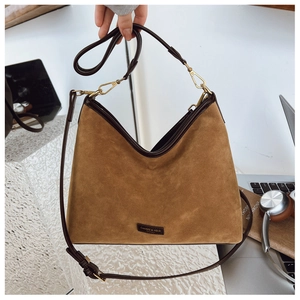 Dettaglio di una borsa tote in pelle scamosciata marrone con bordi scuri e ganci in metallo