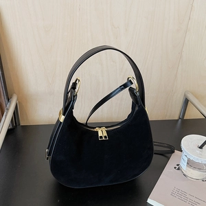 Detail of black crescent handbag featuring suede leather texture and gold metal zipper hardware
