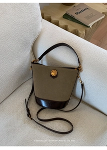 Detailed macro view of khaki suede bucket bag with gold fashion hardware on a sofa