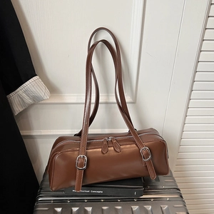 Detail of a brown vintage cylinder bowling bag featuring dual adjustable slim straps