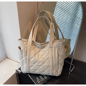 Détail du grand sac fourre-tout beige matelassé avec surpiqûres et poche latérale