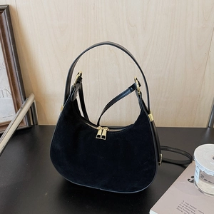 Detail of black suede and leather hobo bag with gold hardware and shoulder strap