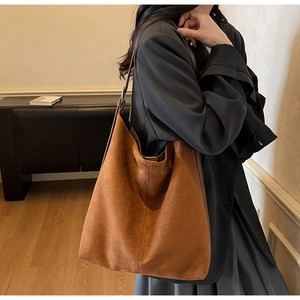 Detail of vintage brown suede tote bag with vertical stitching and metal buckle strap