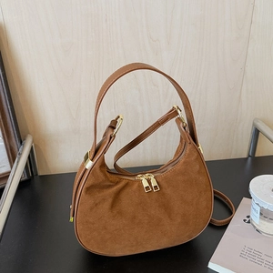 Detailed close-up of brown suede moon bag with golden hardware and vintage matte texture