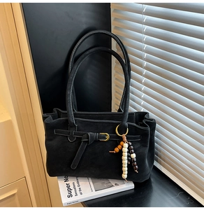 Detail of black matte suede bucket bag with gold buckle and wooden bead charm