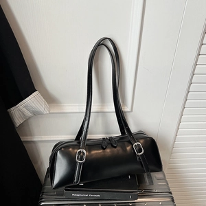 Detail of black cylindrical shoulder bag with matte leather and silver buckle accents