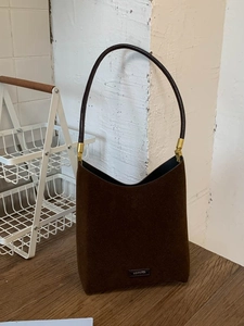 Vintage dark brown suede shoulder bucket bag with NO FILTER metal tag on wooden surface