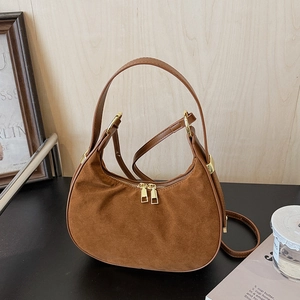 Detailed close-up of brown suede hobo bag with golden hardware and smooth strap detail