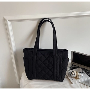 Detail view of black quilted nylon tote bag with rhombus stitching and side pocket