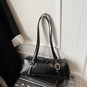 Close-up of minimalist black leather underarm bag with silver buckles and dual zippers