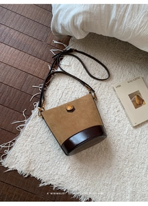 Close-up of retro bucket bag in brown suede and leather on a cozy white rug