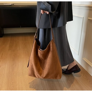 Detailed texture of dark brown suede hobo bucket bag with slim leather strap handle